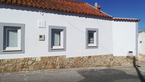 A white building with a red-tiled roof, stone foundation, and three windows. - Casa da Avó near the beaches of the western zone (Óbidos)