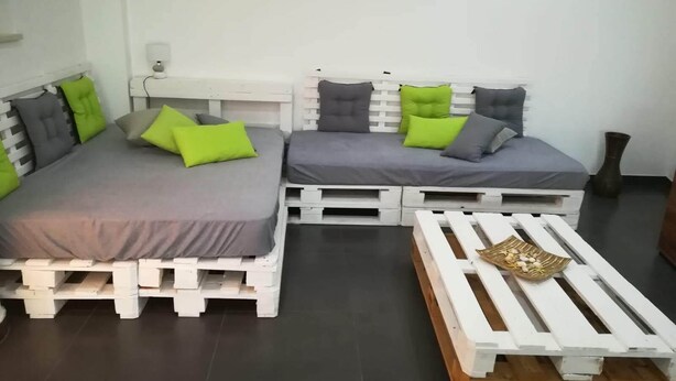 A room with two beds made of white pallets, grey bedding, and green and grey pillows. - Casa da Avó near the beaches of the western zone (Óbidos)