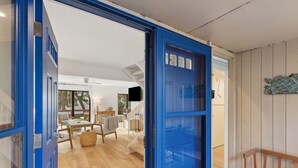 An open blue door leading to a room with a wooden floor, a dining table, and a bench. - 2135 Beachwood - Delightful Town-home with calming views in a Relaxed Setting (Fernandina Beach)