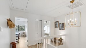 A modern interior with a staircase, white walls, and a chandelier. - 2135 Beachwood - Delightful Town-home with calming views in a Relaxed Setting (Fernandina Beach)