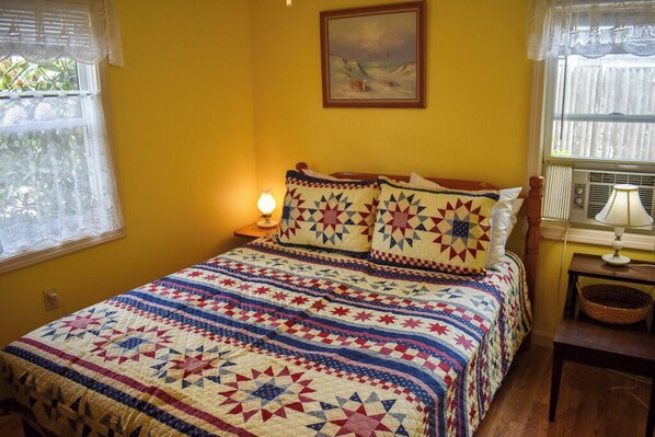 Een kamer met een bed, een schilderij aan de muur en een raam met kantgordijnen.