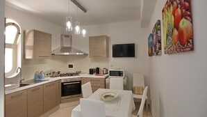 A modern kitchen with white cabinets, a gas stove, and a dining area with a table and chairs.