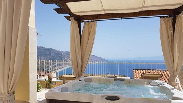 A hot tub with a view of the sea and mountains.