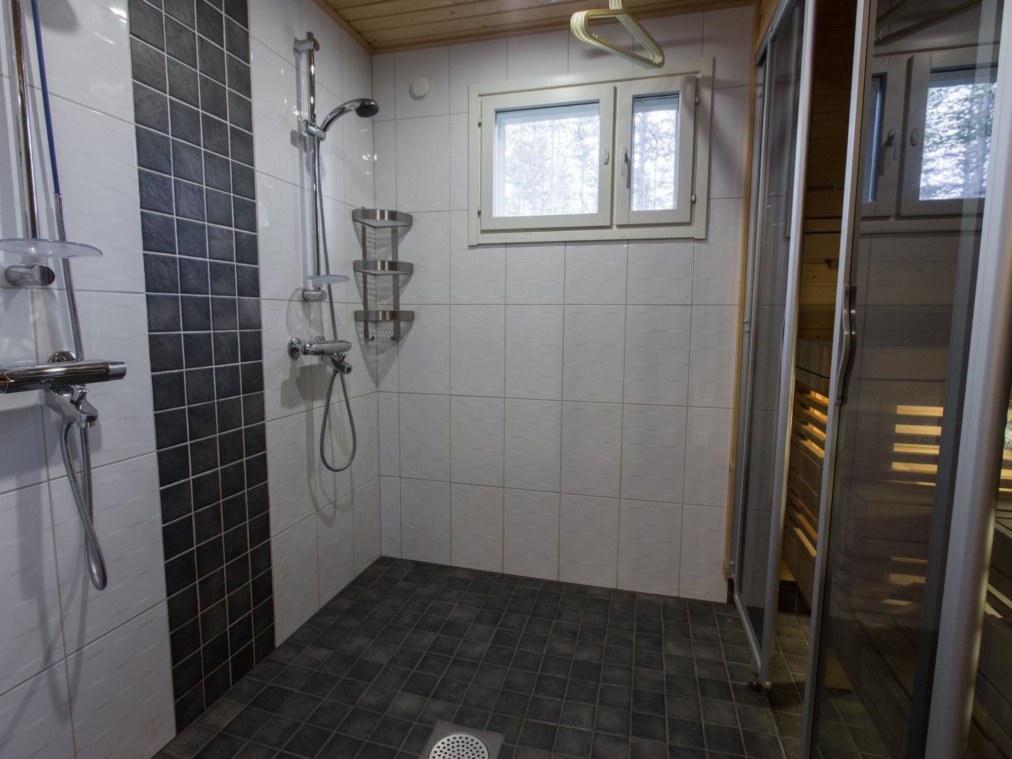 Un espace douche doté d’une porte en verre, d’un pommeau de douche et d’une fenêtre située au-dessus de la douche.