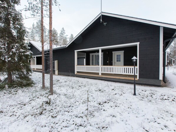 A two-story cabin with a covered porch and a small deck.