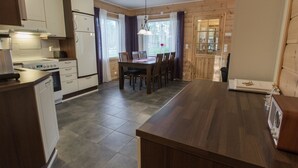 Una cocina moderna con armarios blancos, una estufa y un comedor con mesa y sillas de madera.
