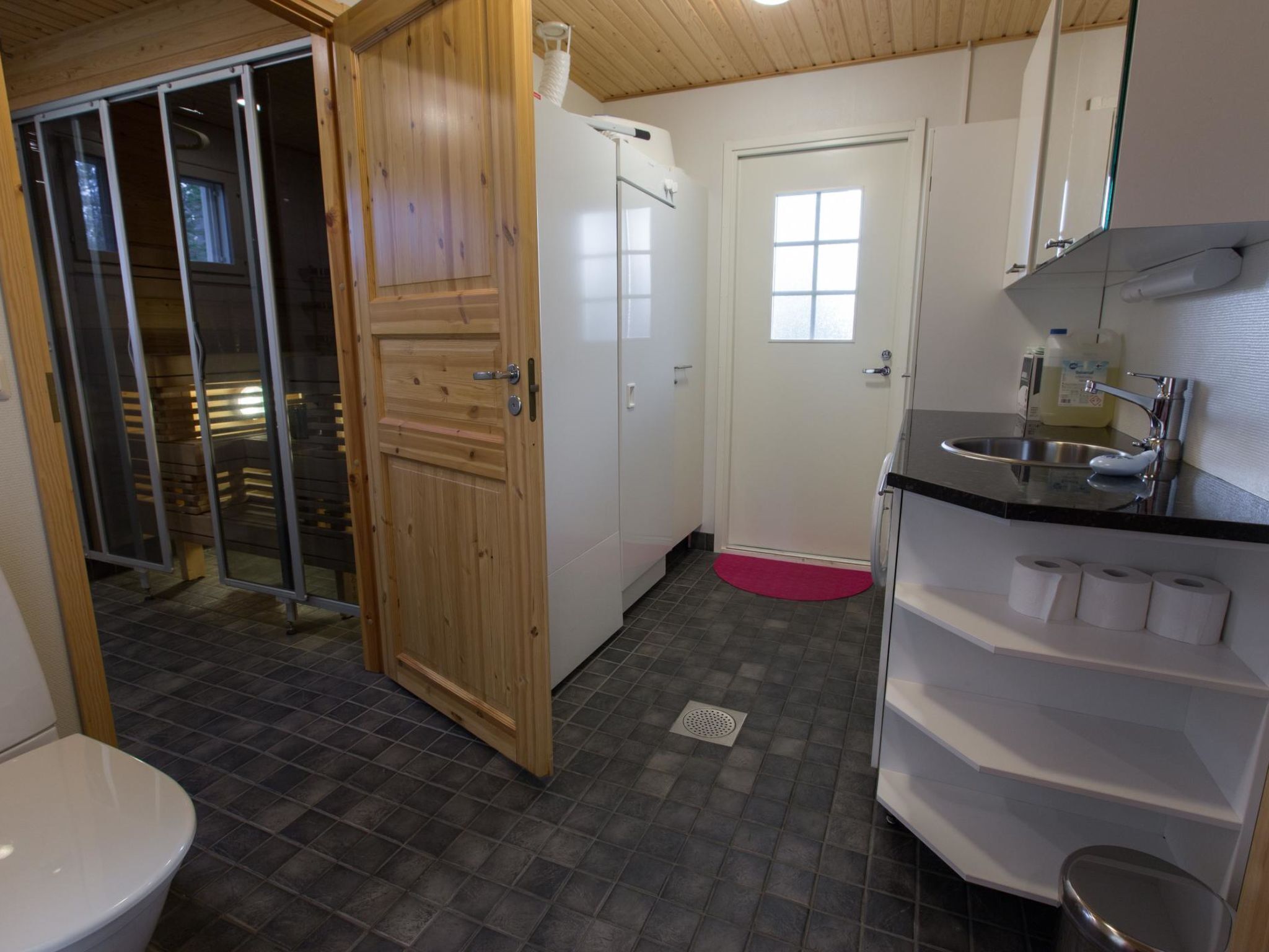 Et lille badeværelse med toilet, håndvask og bruseområde.