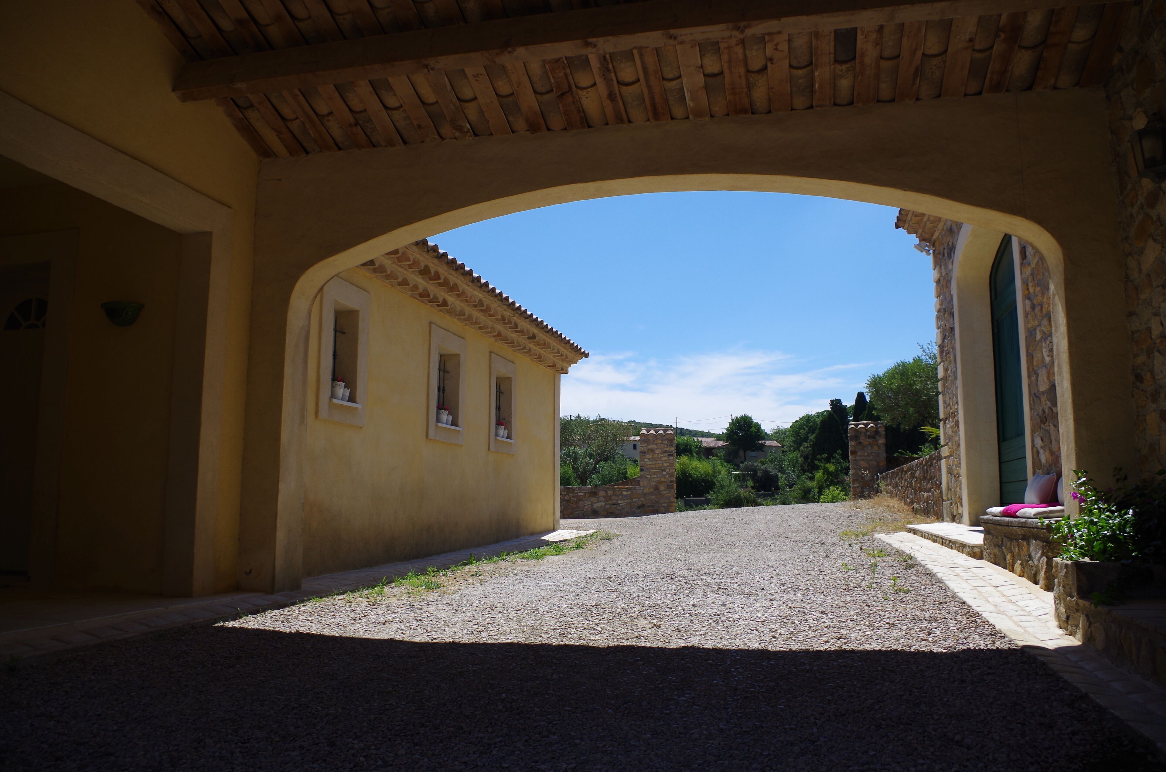 Un patio con muro de piedra, un edificio amarillo y un cielo azul despejado.