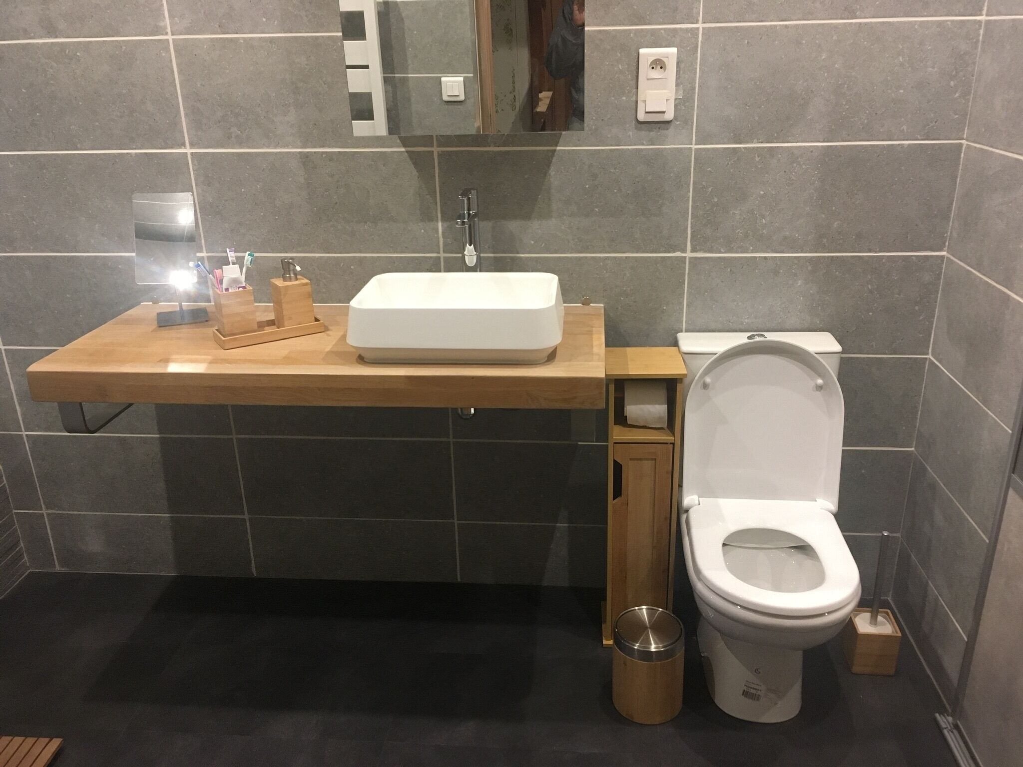 Une salle de bain moderne avec un meuble-lavabo en bois, un lavabo blanc et des toilettes.