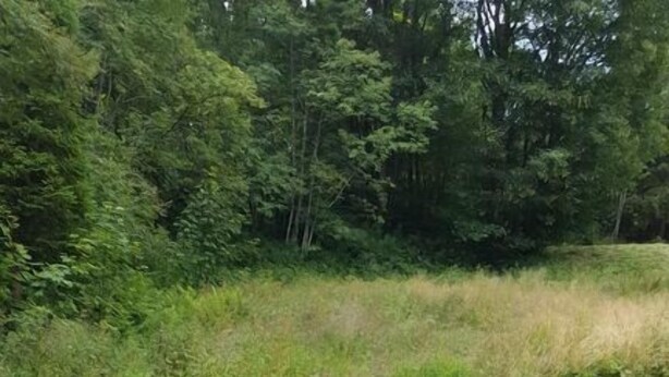 Eine Statue, die eine Person auf Felsen sitzend zeigt, mit einer Steinstruktur im Hintergrund.