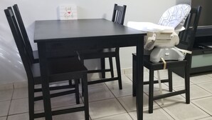 Uma mesa de jantar com quatro cadeiras, um trocador para bebês e uma pequena caixa branca com um símbolo de coração.