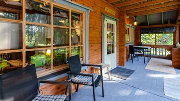 A wooden cabin with a porch, a dining table, and chairs.
