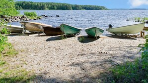 Hiekkainen ranta, jonka reunalla on useita ankkuroituina olevia veneitä.
