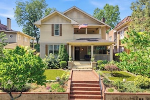A two-story house with a front porch, a flag, and a well-maintained garden. - The Classy Craftsman - Beautiful Decor & Pool (Atlanta)