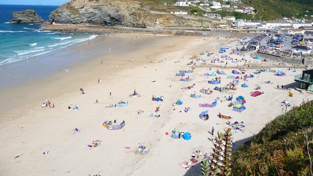 Une plage avec de nombreux parasols et beaucoup de monde.