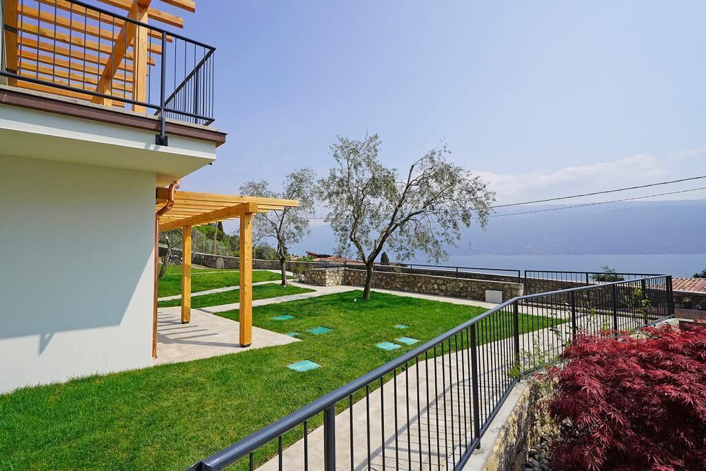 Un balcon agrémenté d’une pergola en bois, d’un mur en pierre et offrant une vue sur la mer.
