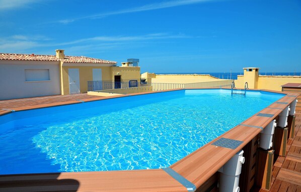 A swimming pool with wooden deck and a view of the sea.