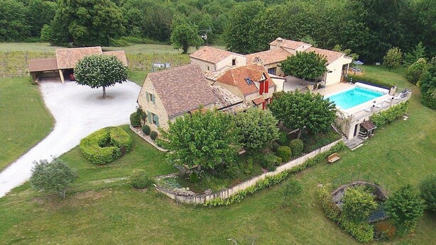 Un'ampia casa circondata da prati curati e alberi, con una piscina.