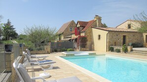 Una piscina con lettini e un edificio in pietra sullo sfondo.