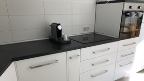 Eine Küche mit weißen Schränken, einer schwarzen Arbeitsplatte und einer Kaffeemaschine.