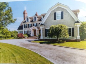 A large, two-story house with a prominent front porch, a driveway, and a well-maintained lawn. - Southampton watermill estate   $3900.00 per night (Water Mill)