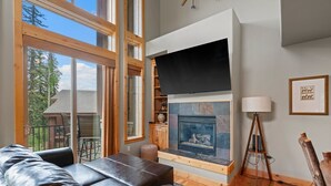 A modern living room with a fireplace, leather sofa, and large windows. - Ping Pong, Foosball, Pet Friendly, Mountain Living (Durango)