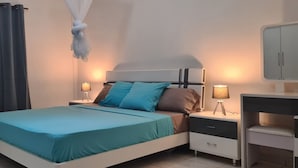 Un dormitorio ordenado con cama, mesitas de noche, una lámpara y un armario.