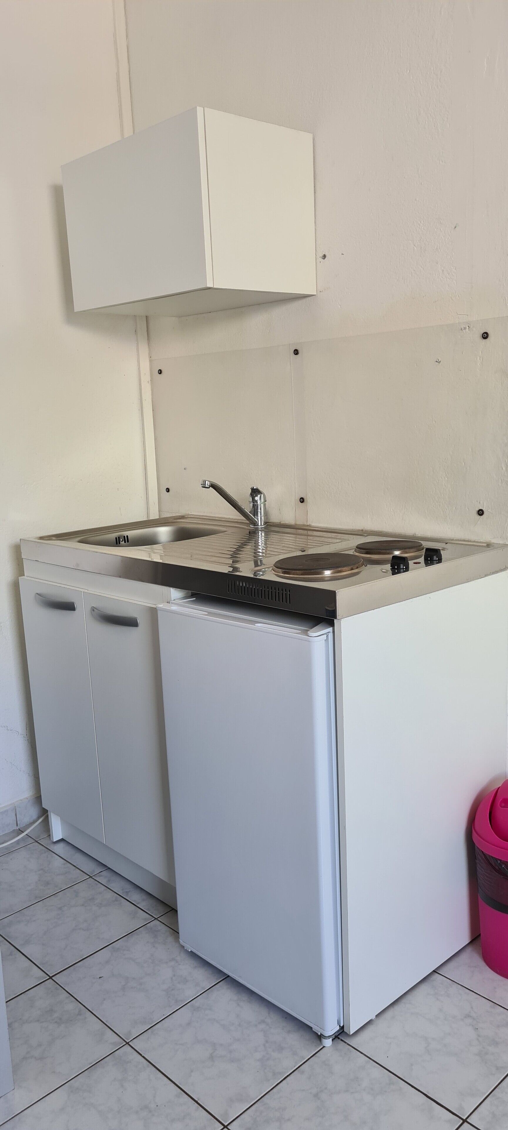 A compact kitchenette with a sink, stove, and storage cabinets.
