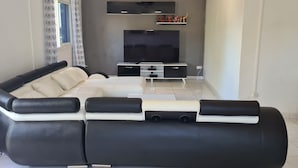 Una sala de estar moderna con un sofá blanco y negro, un televisor de pantalla plana y un mueble de entretenimiento pequeño.