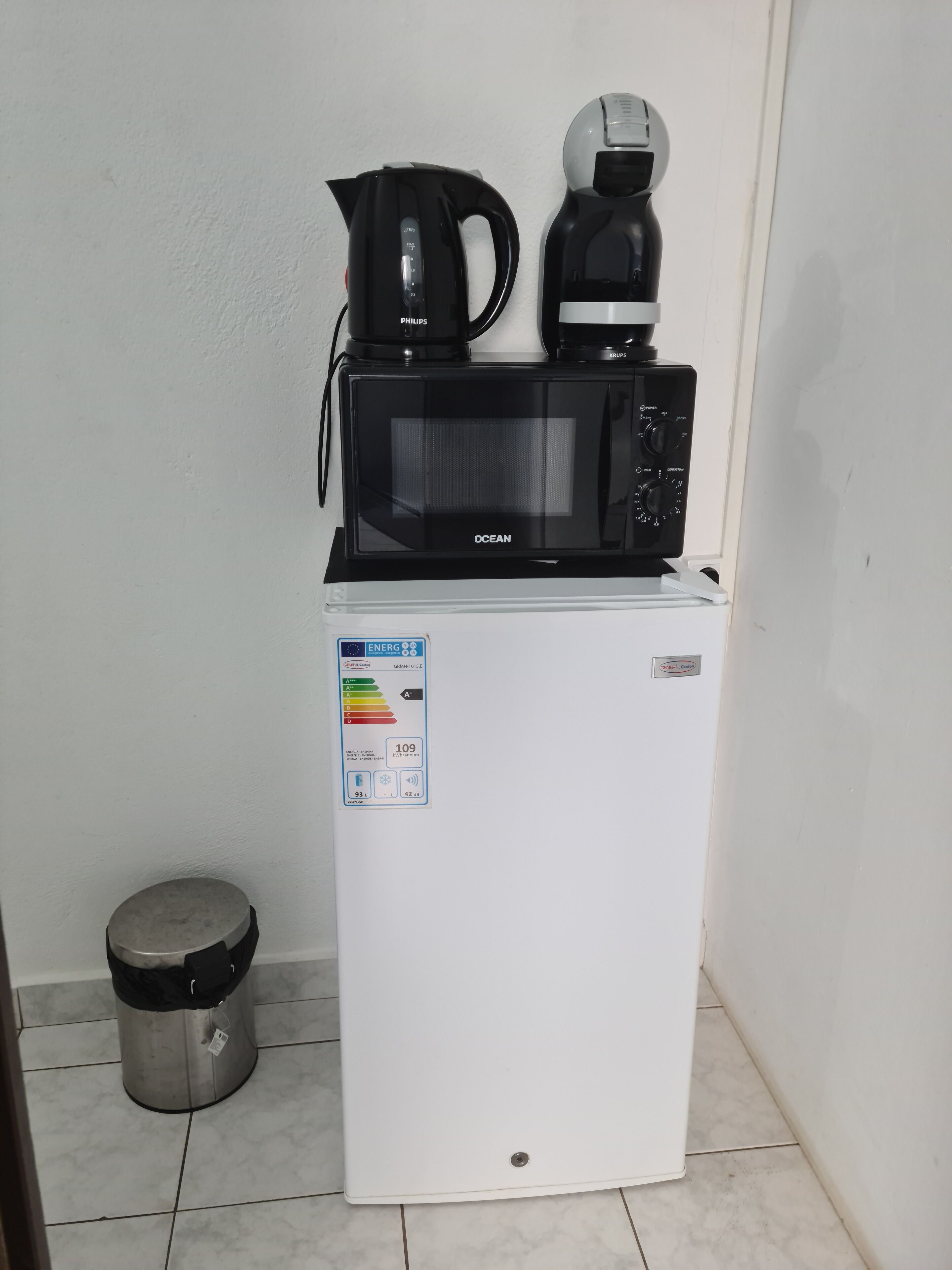 A compact white refrigerator with a coffee maker and a microwave on top.