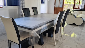 Un comedor con una mesa rectangular, sillas blancas y negras, y un sofá.