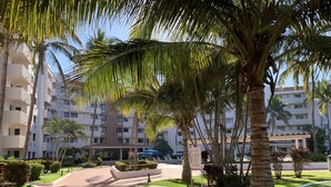 A resort with a central pathway, palm trees, and a building with balconies.