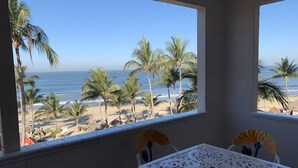 A room with a view of a beach, palm trees, and the ocean.