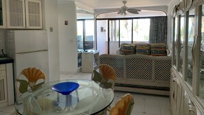 A dining area with a glass table, chairs, and a ceiling fan.