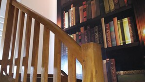 Eine Holztreppe führt zu einem Bücherregal voller Bücher.