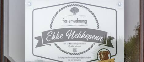A sign for 'Ekke Nackkeppenn' hotel with contact information and a QR code.