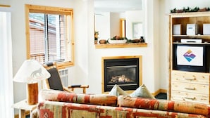 Una sala de estar con chimenea, un sofá, un televisor y una estantería de madera.