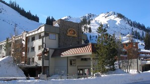 Un edificio de varios pisos con fachada de piedra y un telesilla al fondo.