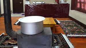 Eine traditionelle Küche mit Herd, Holztisch und Regalen mit gerahmten Bildern.