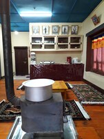 Una cocina tradicional con estufa, mesa de madera y repisas con cuadros.