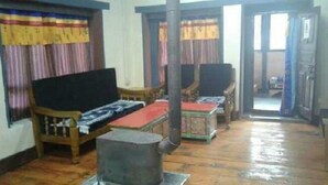 Ein Zimmer mit einer Couch, einem kleinen Tisch und einem Sessel. Eine Tür führt in einen weiteren Raum.