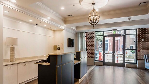 A spacious lobby with a reception desk, a chandelier, and a view of the street through large glass doors. - The King 583 in Charleston (Charleston)