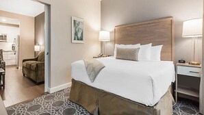 A hotel room with a large bed, a bedside table with a lamp, a chair, and a view into the kitchen area. - The King 583 in Charleston (Charleston)