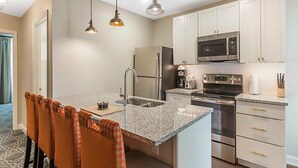 A modern kitchen with granite countertops, stainless steel appliances, and white cabinetry. - The King 583 in Charleston (Charleston)