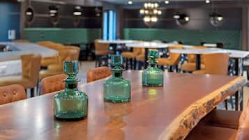 Un interior de restaurante con mesas de madera y decantadores de vidrio verde.