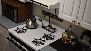 Una cocina equipada con estufa, microondas, tetera y un letrero que dice 'enjoy the journey'.