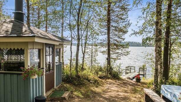 A cabin with a view of a lake, a dock, and a bench.