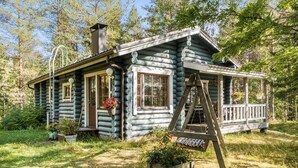 A log cabin with a porch and a swing set.