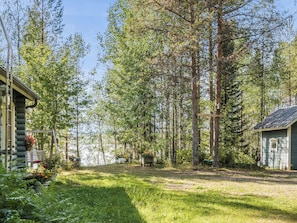 Une cabane entourée de grands arbres et bordée d’une pelouse.