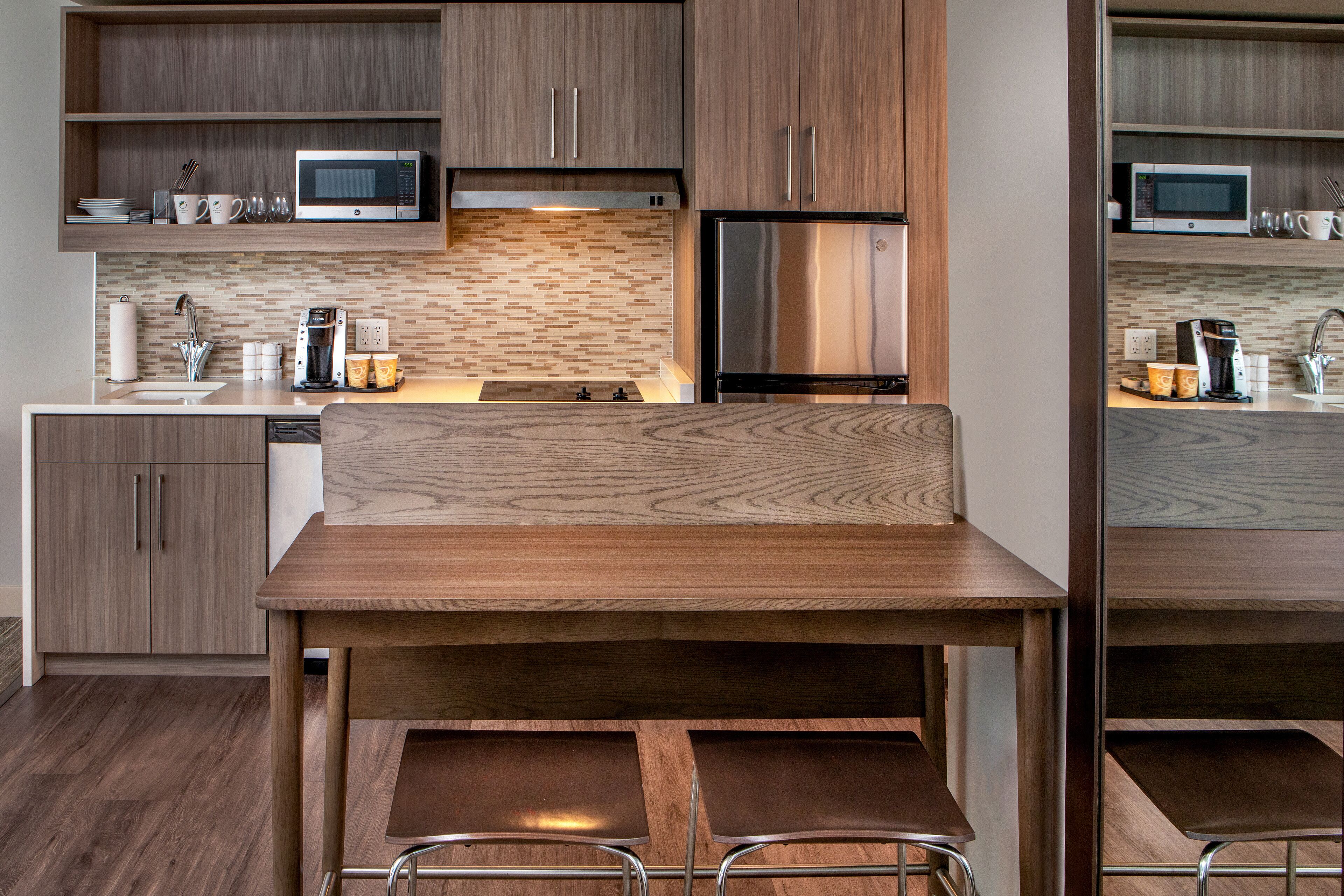 Una cocina moderna con armarios de madera, un refrigerador de acero inoxidable, un microondas y una cafetera.